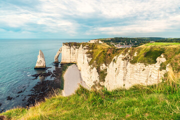 White chalk cliffs and natural arches Aval and Needle of Etretat and beautiful famous coastline during low tide, Normandy, France. French sea coast in Normandie with famous rock formations at sunset