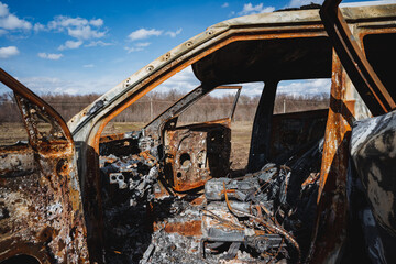 burnt fat of a car abandoned on the side of the road in a field, a burnt car, a car crime,...