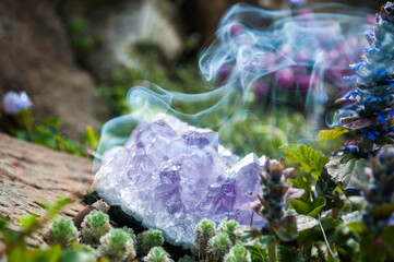 Plants and crystals in the rock garden. Ajuga tenorii, bugleweed, ground pine, carpet bugle. Esoteric background with incense smoke.