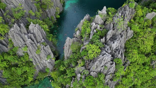 Aerial top view of tropical island with people. Tourists leisure in blue lagoons, rocks cliffs mountains and coral reef, Philippines, 4k