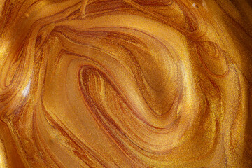 Closeup of golden fluid metallic acrylic paint textured background