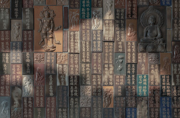 Chinese lettering teachings and Carved buddha images into a slab of colored tiles on temple wall of...