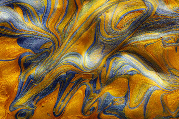 Closeup of golden and blue fluid metallic acrylic paint textured background