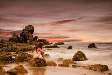 Woman in romantic attitude sitting on a rock at the seashore, Asturias-Spain II