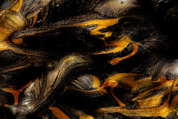 Closeup of gold and black fluid metallic paint textured background