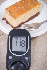 Glucometer with high result sugar level and portion of sweet cheesecake. Nutrition during diabetes