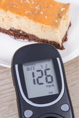 Glucometer and portion of cheesecake. Measuring and checking sugar level during diabetes