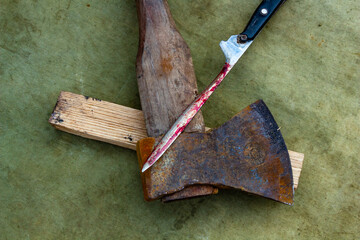 A rusty axe, a knife with blood, a wooden block, tools of labor in the village