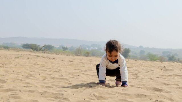 innocent toddler playing with sand at desert at day from flat angle