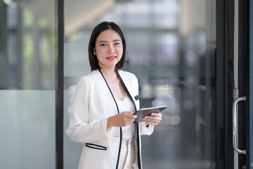 Smiling professional businesswoman holding a tablet in a contemporary office setting