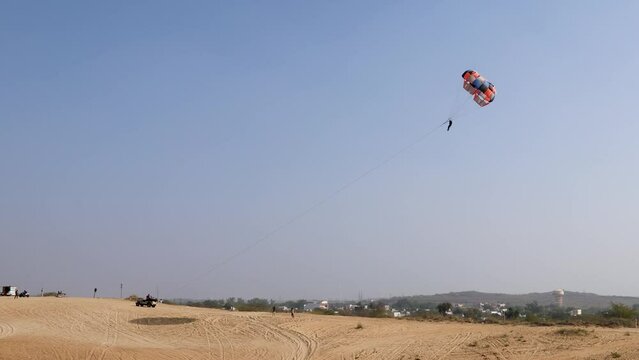 parasailing adventure activity at desert with bright blue sky background at day from flat angle