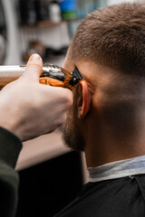Master trims client hair with professional tool in luxury barbershop closeup. Barber does straight...