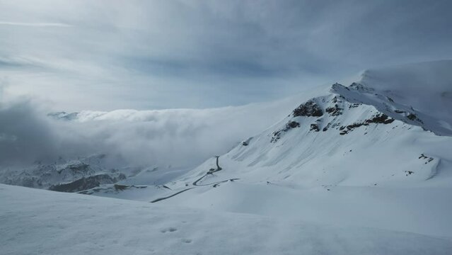 Grossgloknershtrasse in snow and clouds. Great high mountain road near Grossglokner mount in Austrian Alps, time lapse 4k