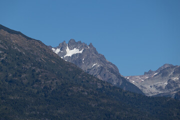 Fototapeta premium Lonely horizontal view of mountain peak with growing vegetation on the bottom, and an infinite clear blue sky on top