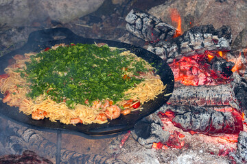 Chilli prawn and tomato spaghetti covered with parsley in the camping frying pan as outdoor cooking and pasta recipes concept