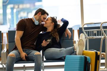 couple sitting lovingly at the airport waiting for their flight to depart