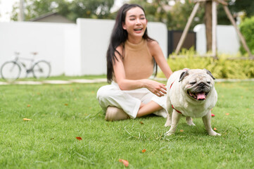 Happy asian woman playing with Cute Smart pug Puppy Dog In the Backyard