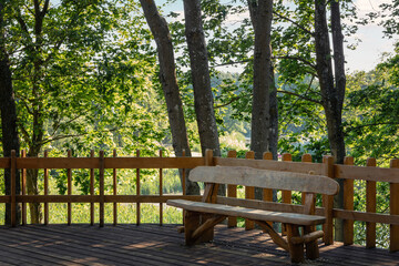 Handmade wooden bench in the recreation and viewing area in green trees background