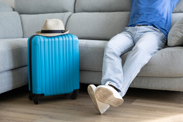 boy with his travel luggage prepared, sitting on the sofa waiting to go on vacation