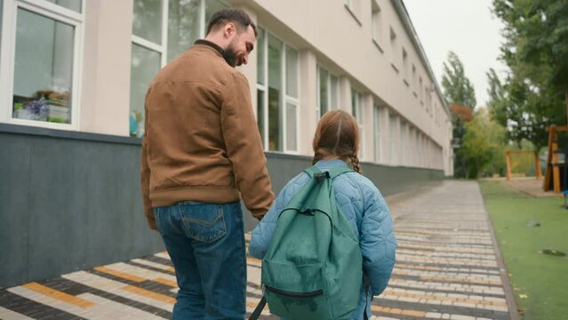 Father and daughter walk city street outside holding hands family support going school child learning kid pupil schoolgirl learner male female schoolbag offspring educational parenting bond together