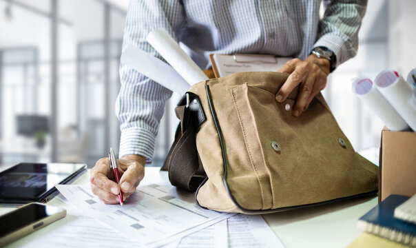 Businessman working  in office writing business report and holding many documents with document bag. after work in office he take his work to home and continue