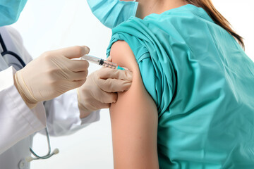 Female doctor or nurse giving shot or vaccine to a patient's shoulder. Vaccination and prevention