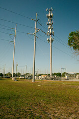 Obraz premium Vertical view near sunset of Electric Substation with High Power Lines in St. Petersburg, Florida. Utility trucks.View over green grass, blue sky with large metal utility poles. No People. Copy space