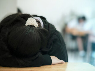 A female student who is tired from taking a difficult exam is discouraged and falls asleep during the exam due to stress. The student collapses on the table inside the exam room