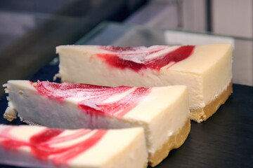 Three slices of creamy cheesecake served on a sleek black plate