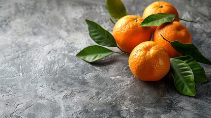 Four oranges with stems arranged on a tabletop
