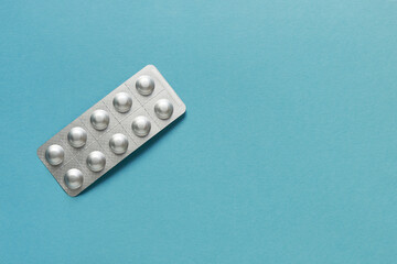 Pills in silver aluminum blister packaging on blue background. Pharmacy products.