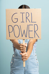 Anonymous woman holding banner GIRL POWER slogan isolated on studio blue background. Women's rights
