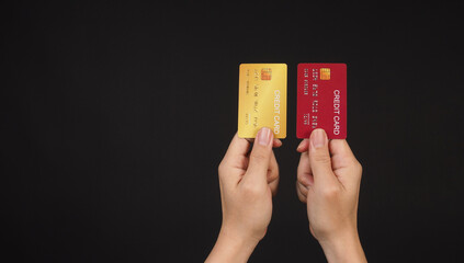 Two hands is hold red and gold credit card on black background.