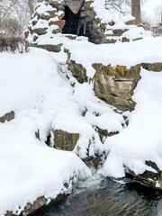 Winter creek with stone wall with snow and ice