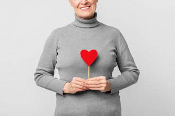 Senior woman holding a heart shape, cropped
