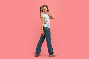 Teen girl walking with headphones on pink