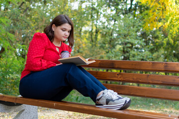 a woman is sitting on a bench reading a book