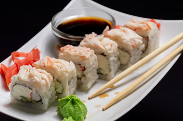Enjoy a plate of sushi with chopsticks and a bowl of soy sauce
