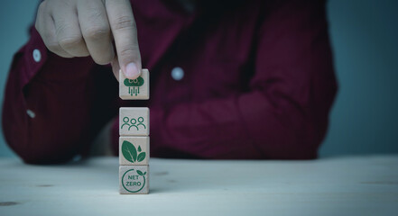 Businessman holding a wooden cube CO2 reduction with the peoples, green leaves, Net Zero icon for green factory to limit global warming..Earth and Green environment, economy concept.