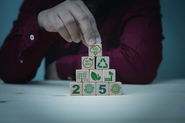 Businessman holding a wooden cube CO2 reducing, solar cell, an electric vehicle, green leaves, Net Zero icon for green factory to limit global warming. Earth and Green environment concept.