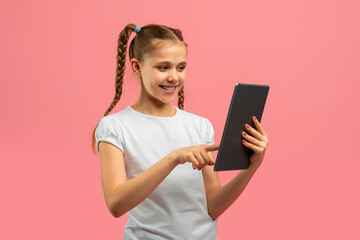 Smiling girl using tablet on pink background