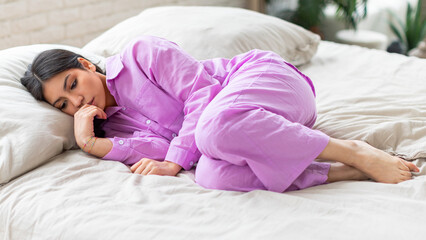 Woman in purple shirt lying on bed