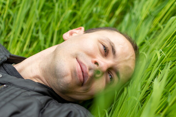 Man laying in grass enjoying nature, eyes closed, feeling content and peaceful