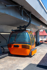 A cable car is parked under a bridge in an urban setting