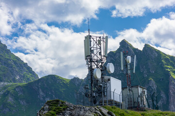 Tower with antennas on hill, mountains in background