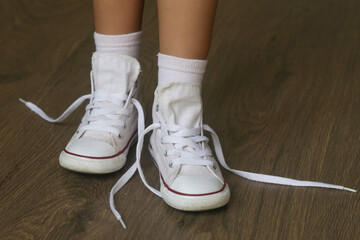 Kid tying shoes. Little girl struggling to tie shoe laces. Child learning fine motor skills.