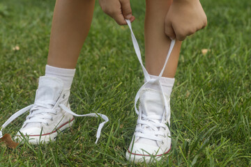 Kid tying shoes. Little girl struggling to tie shoe laces. Child learning fine motor skills.	
