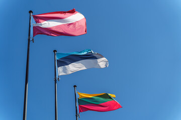 The flags of the three Baltic countries, Lithuania, Latvia and Estonia flutter against a clear blue sky