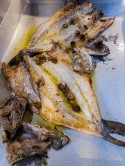 "View of a baking tray with a horse mackerel, a fish open and freshly cooked in the oven, ready to be served and eaten.