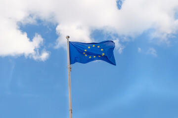 EU flag waving on blue sky background with clouds
